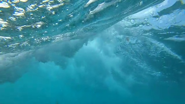 慢镜头，水下:深蓝色的大海波涛破碎溅起水花。视频素材