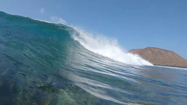 慢动作，水下:小管波冲向岩石海岸的Lobos。视频素材