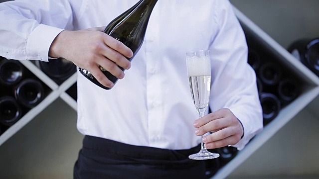 餐厅里的侍者把香槟从瓶子里倒进玻璃杯里视频素材