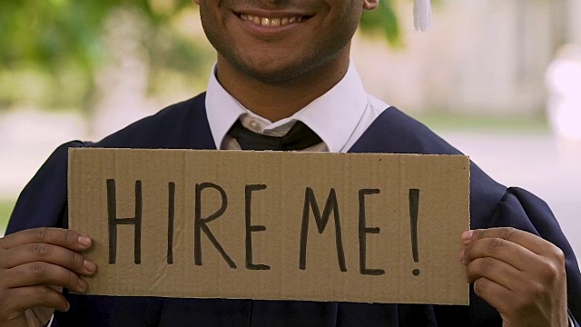 名牌大学毕业生举着牌子，上面写着雇用我，事业视频下载