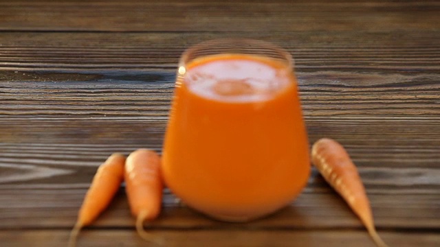 胡萝卜汁放在桌子上的玻璃杯里视频素材