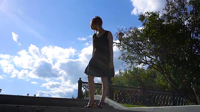 在风中，公园楼梯顶上穿着黑色短裙的浪漫女子的剪影。视频下载