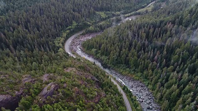 航拍镜头飞过河床，旁边是蜿蜒的道路和郁郁葱葱的绿色森林。视频下载