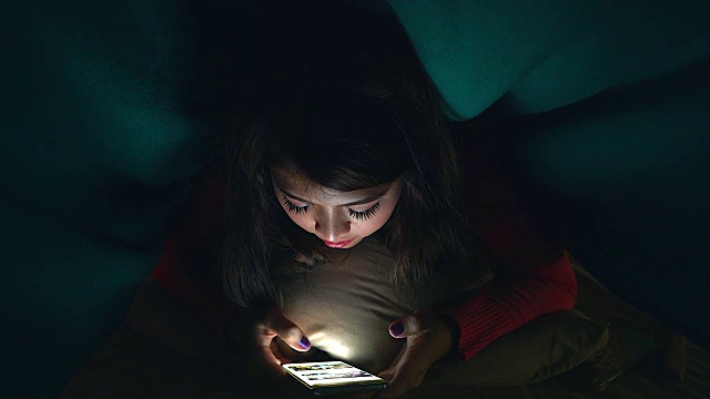 晚上躺在床上看手机或与人聊天的年轻女孩或青少年。视频下载