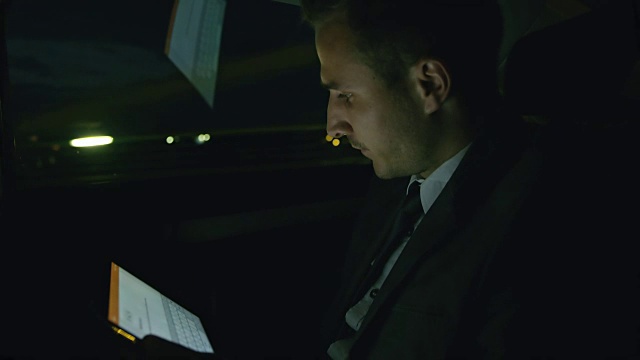 微软商人晚上在出租车后座上使用平板电脑视频素材