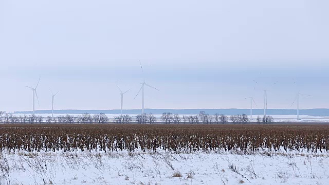 在远处雪地里旋转的风力涡轮机视频素材