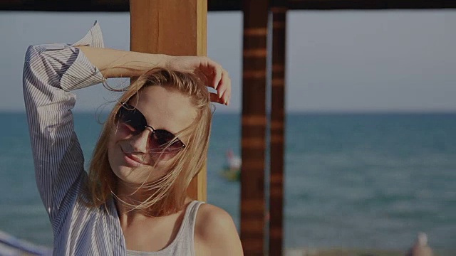 戴着太阳镜的女孩微笑着躺在大海的背景上视频下载