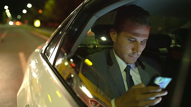 微软商人晚上在出租车上使用智能手机视频素材