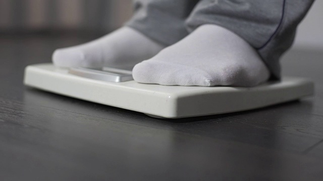 懒惰肥胖的男性踩在浴室秤上，控制体重和节食视频下载