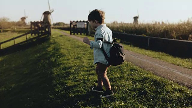 两个小孩在老风车农场附近玩耍。快乐的孩子们绕着乡村风景奔跑。幸福和快乐。4 k视频素材