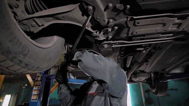 专业的机器修理工检查机器的底部，他看车轮和其他汽车零件视频素材