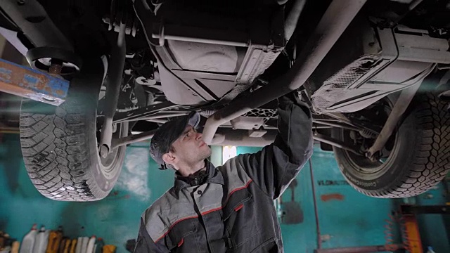 一个成年人在轮胎维修厂检查汽车的状况，工人检查机器的状况视频素材