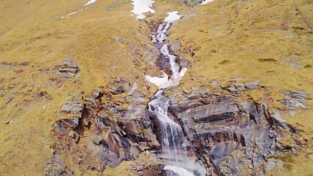 空中飞行向后移动远离瀑布，在黄山边瀑布建立。户外高山雪景是秋冬野外自然景观。4k无人机飞行建立镜头视频素材