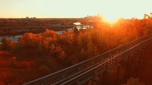 鸟瞰图女子慢跑过木桥在日落，城市在远处视频素材