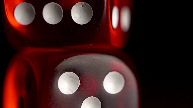 黑色背景上的两个红色骰子。装有骰子和彩带的小酒杯。风险概念-玩骰子在黑色木制背景。用骰子玩游戏红色赌场掷骰子视频下载