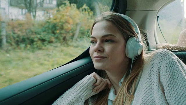 微笑的女孩在车后座听音乐视频素材