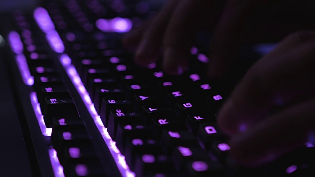 手打字在多色Led键盘在黑暗环境的特写与模糊的背景视频素材