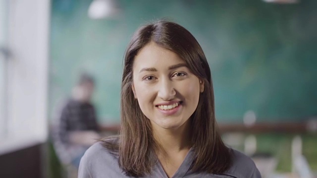 美丽的亚洲女人在现代办公室的肖像。年轻成功的女商人微笑着看着镜头视频素材