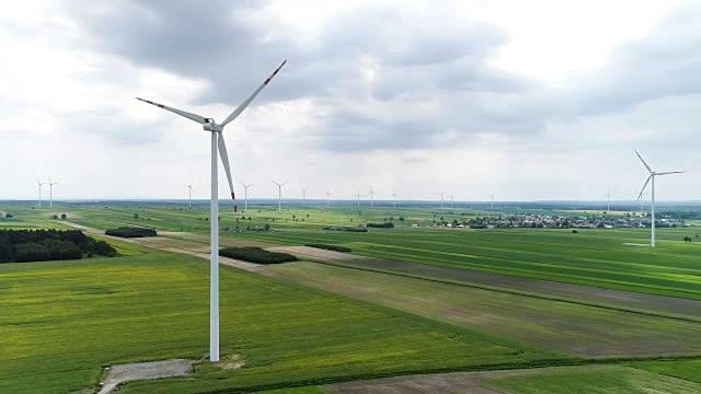 风力涡轮机矗立在油菜和小麦盛开的田野上视频素材
