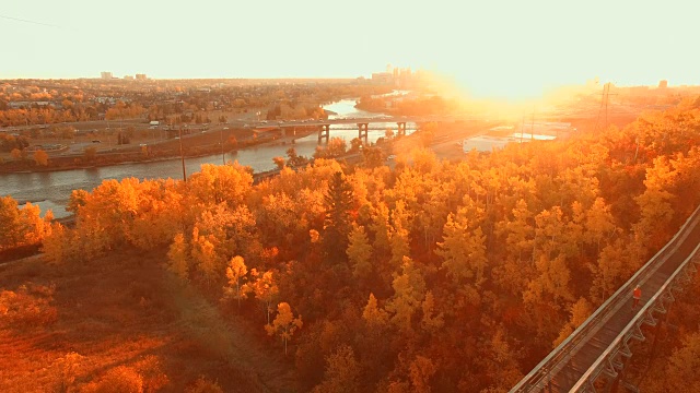 鸟瞰图女子慢跑过木桥在日落，城市在远处视频素材