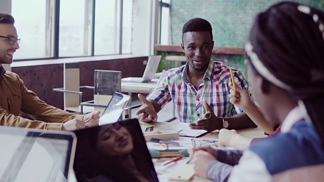 创意商务团队会议在现代办公室。一群不同种族的年轻人讨论着创业的想法，大笑着视频素材