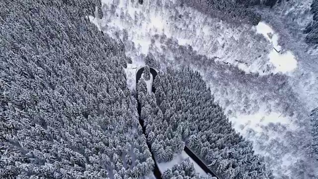 前空中鸟瞰图上的发夹弯转弯公路在山区积雪覆盖的冬季森林。白松树林。雪街道道路建立。4k无人机直飞建立视频素材