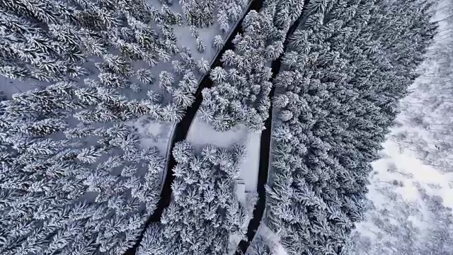 空中鸟瞰图上的发夹弯转弯公路在山区积雪覆盖的冬季森林。白松树林。雪街道道路建立。4k无人机直飞建立视频素材