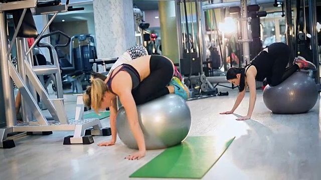 妇女在健身房里用健身球做运动视频素材