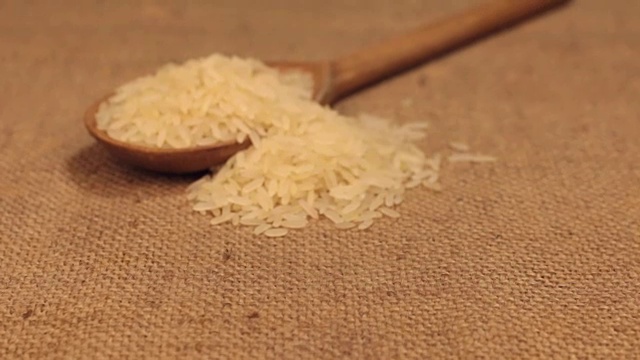 近似的木勺溢出米粒，躺在粗麻布上视频素材