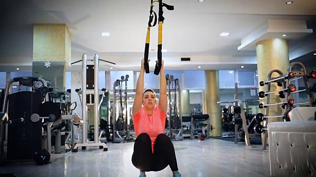 在健身房用吊带做手臂运动的女人视频素材