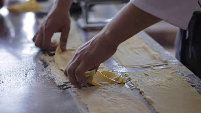 厨师用手切意大利面。新鲜的意大利面从意大利面机里出来，慢动作视频素材