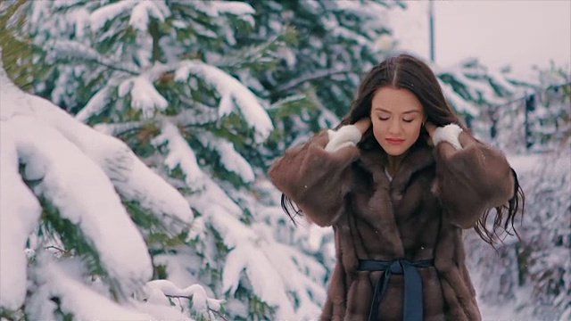 深褐色的女孩穿着棕色的毛皮大衣在冬天慢动作的走着视频下载