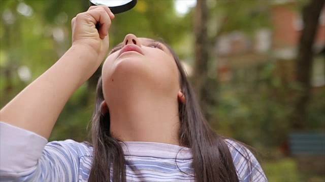 可爱的小女孩拿着放大镜的肖像视频素材