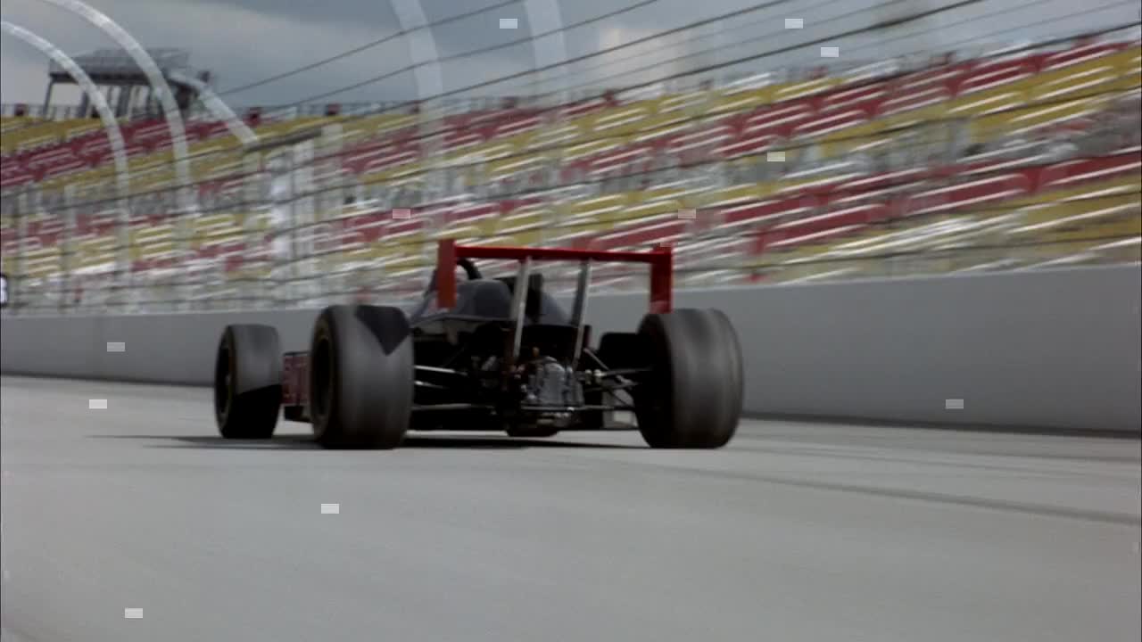 手持跟踪一辆红白条纹一级方程式赛车在赛道上与一辆带有红星的黑色赛车比赛。看汽车的后面。视频下载