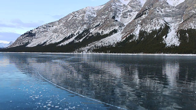 年轻人在美丽的山间湖泊上单飞溜冰视频素材