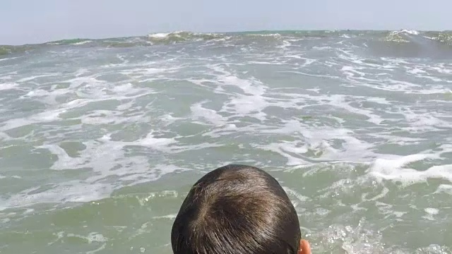 男孩在水里等待着即将到来的波浪视频素材