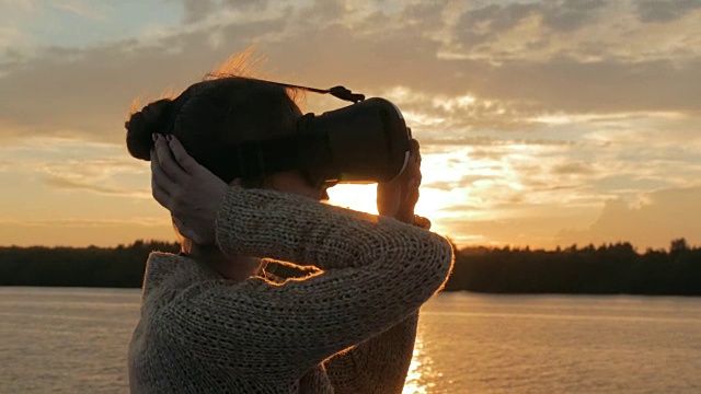日落时分，一名女子在游轮甲板上戴着虚拟现实眼镜视频素材