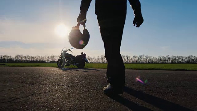 向前看，去梦想和旅行。一个骑摩托车的人手里拿着头盔走向摩托车视频素材
