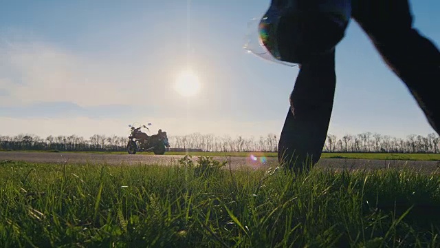 一个摩托车手拿着头盔，看着摩托车的剪影视频素材