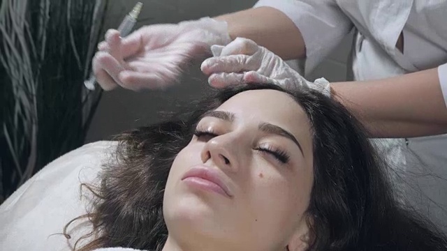 英俊的女人被打了一针。这个过程让医生戴上白手套。中间疗法的概念。推动以加强头发和它们的生长视频素材