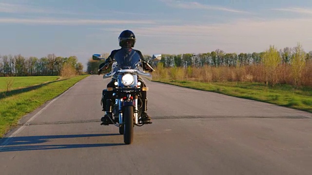 在一条狭窄的柏油路上骑摩托车的人视频素材
