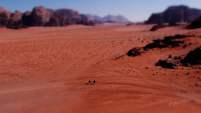 微型效应WS:在中东约旦的瓦迪拉姆，骆驼上的小贝都因人穿过令人惊叹的沙漠风景。Tilt-Shift。视频素材