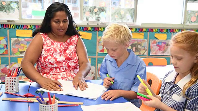 土著小学教师与男孩和女孩在他们的书桌视频素材
