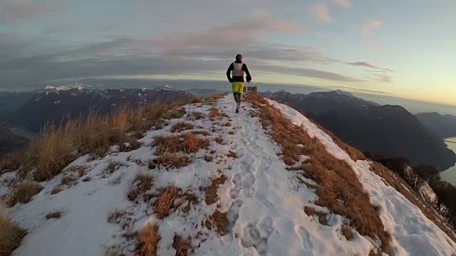 日落时分，成年雄性在湖上的雪山脊上奔跑视频下载