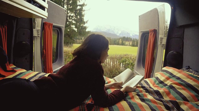 一个女人在露营车里看书，可以看到阿尔卑斯山视频下载