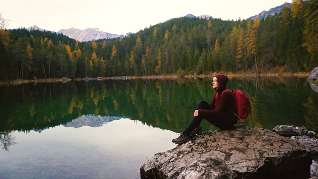 一个女人坐在岩石上，看着阿尔卑斯山Eibsee湖的风景视频素材