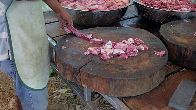肉贩用切肉刀在圆形木砧板上切一块肉视频素材