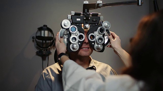 OTS女士。验光师与病人聊天，因为她在他的眼睛前移动视光仪在例行检查。视频素材