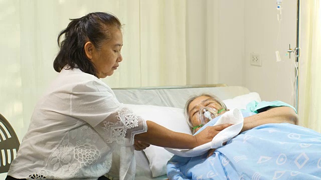 一位妇女正在医院病床上照顾她的母亲视频素材