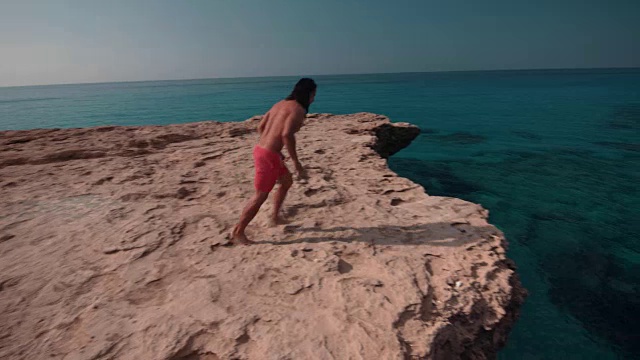 年轻人纵身跳下悬崖，跳入大海视频素材
